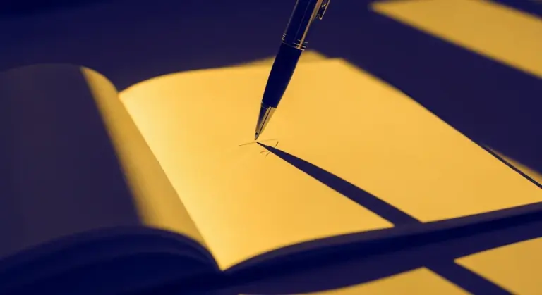 A fountain pen rests on the open pages of a blank yellow notebook